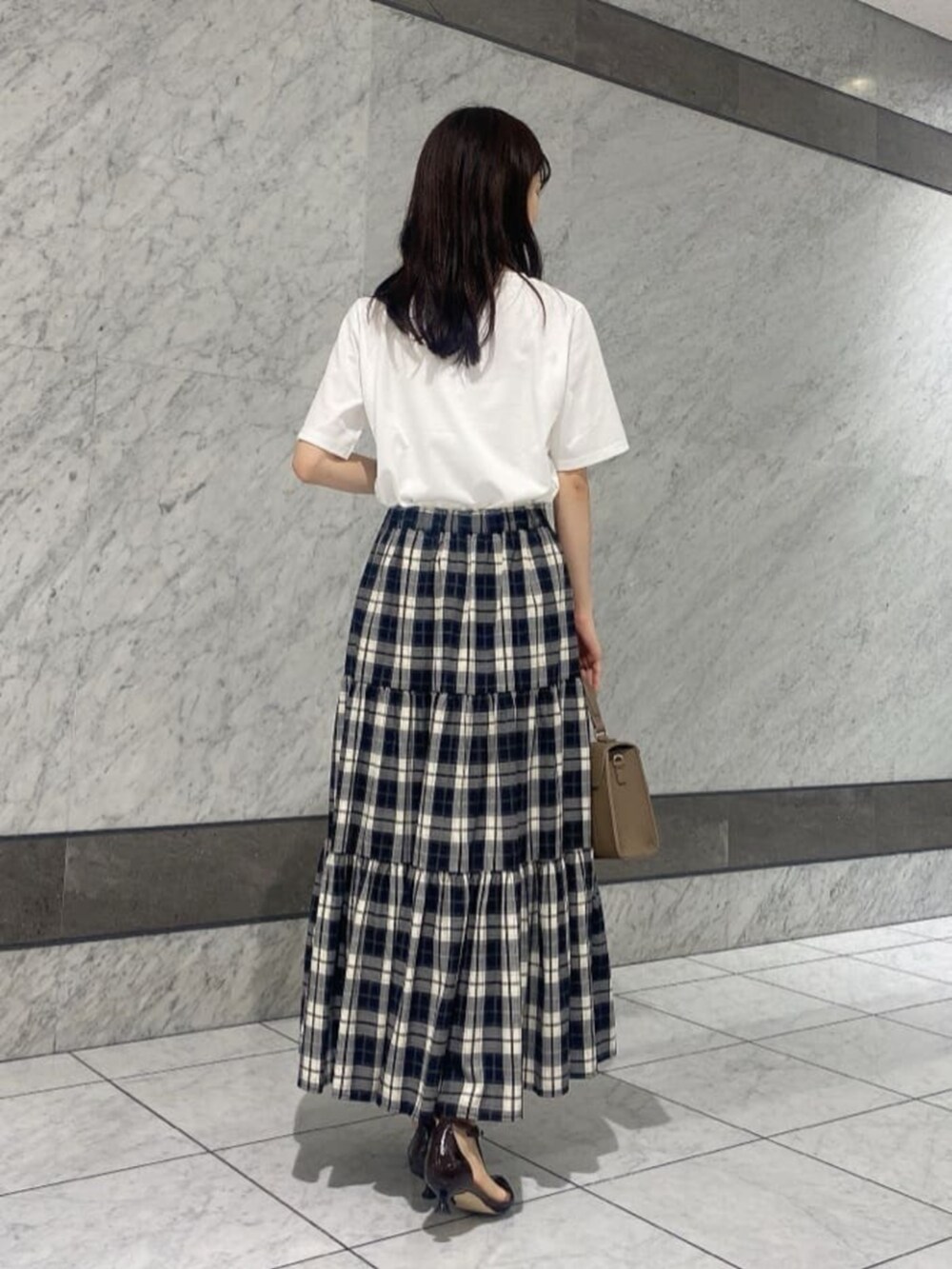 ホワイト系のTシャツ/カットソー、ベージュ系のスカートを着用したレディースの秋コーディネートの2枚目の写真