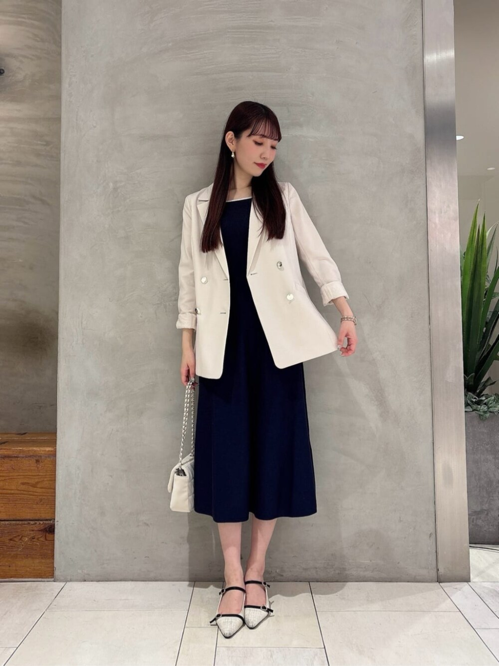 ホワイト系のテーラードジャケット、ホワイト系のショルダーバッグ、ブルー系のワンピースを着用したレディースの春コーディネートの2枚目の写真