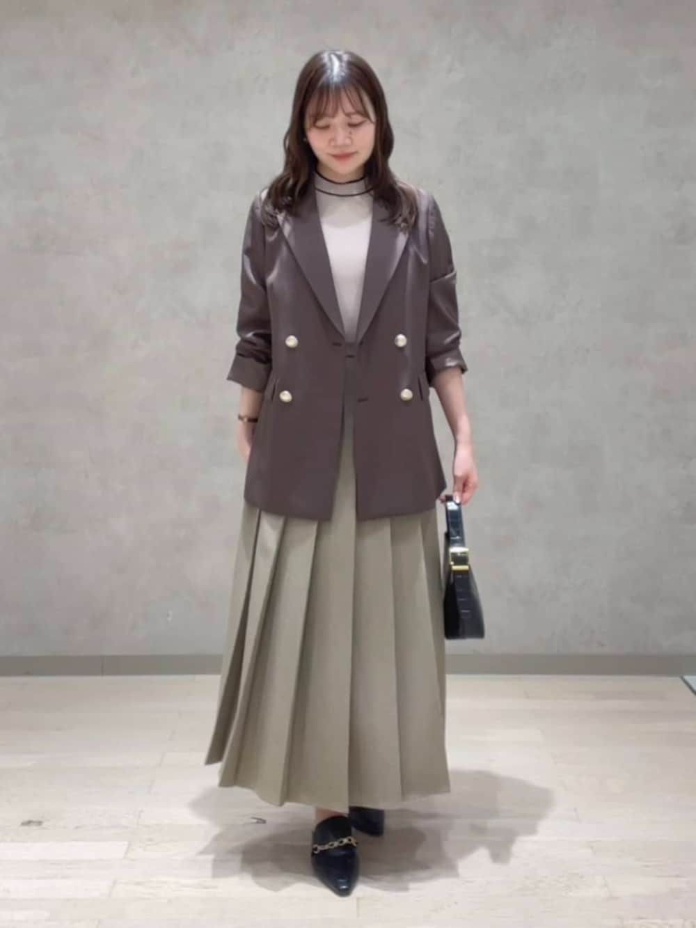 ブラウン系のテーラードジャケット、ベージュ系のニット/セーター、ブラウン系のスカートを着用したレディースの秋コーディネートの2枚目の写真