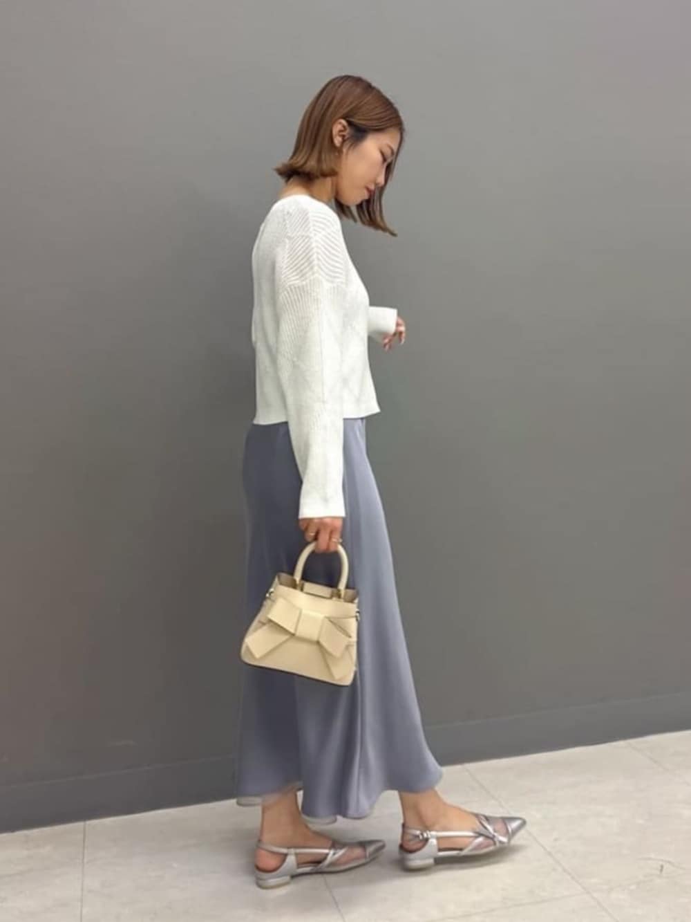 ホワイト系のショルダーバッグ、ホワイト系のニット/セーター、グレー系のスカートを着用したレディースの春コーディネートの3枚目の写真