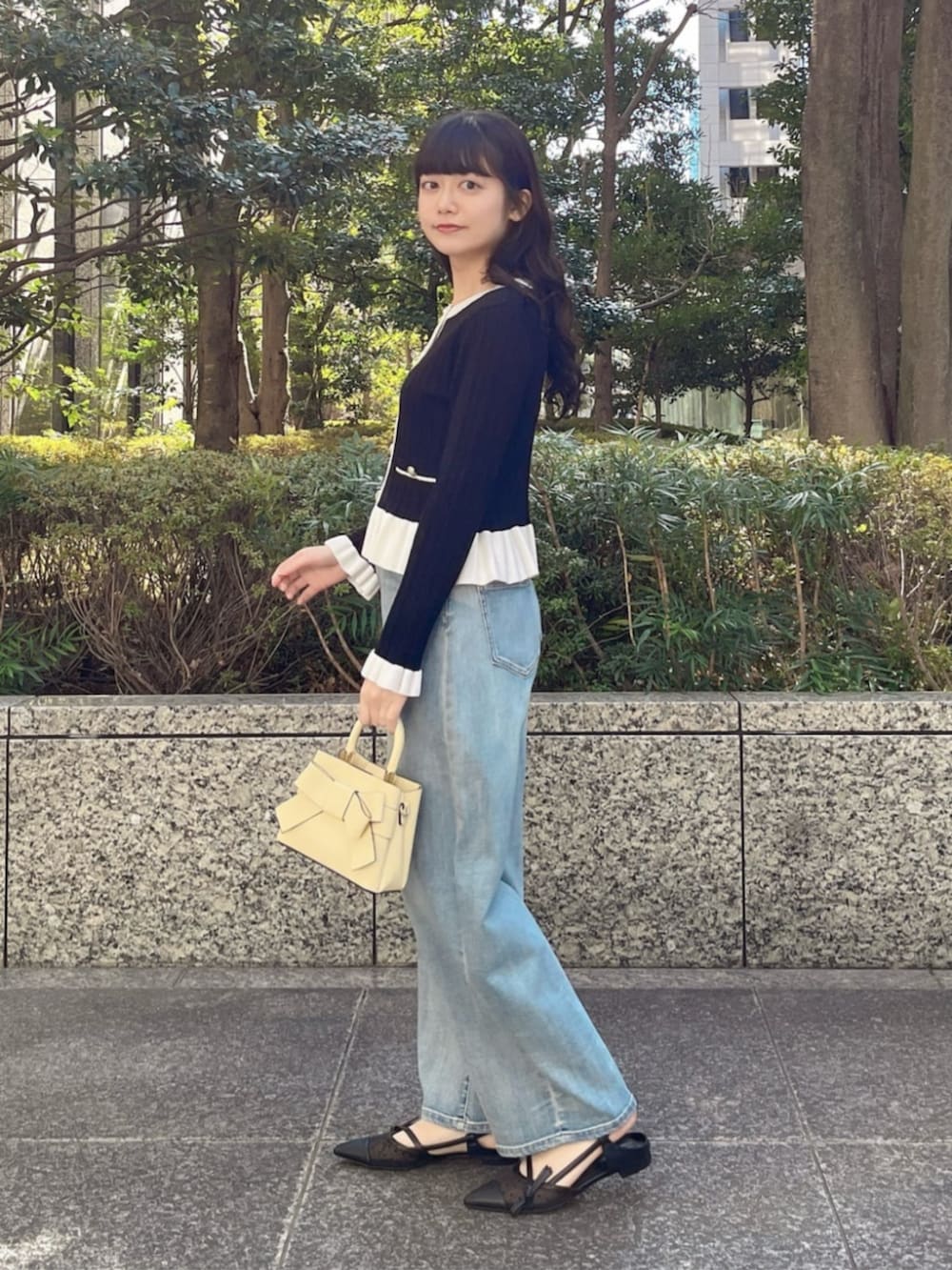 イエロー系のショルダーバッグ、ブルー系のデニムパンツ、ブラック系のパンプスを着用したレディースの春コーディネートの2枚目の写真