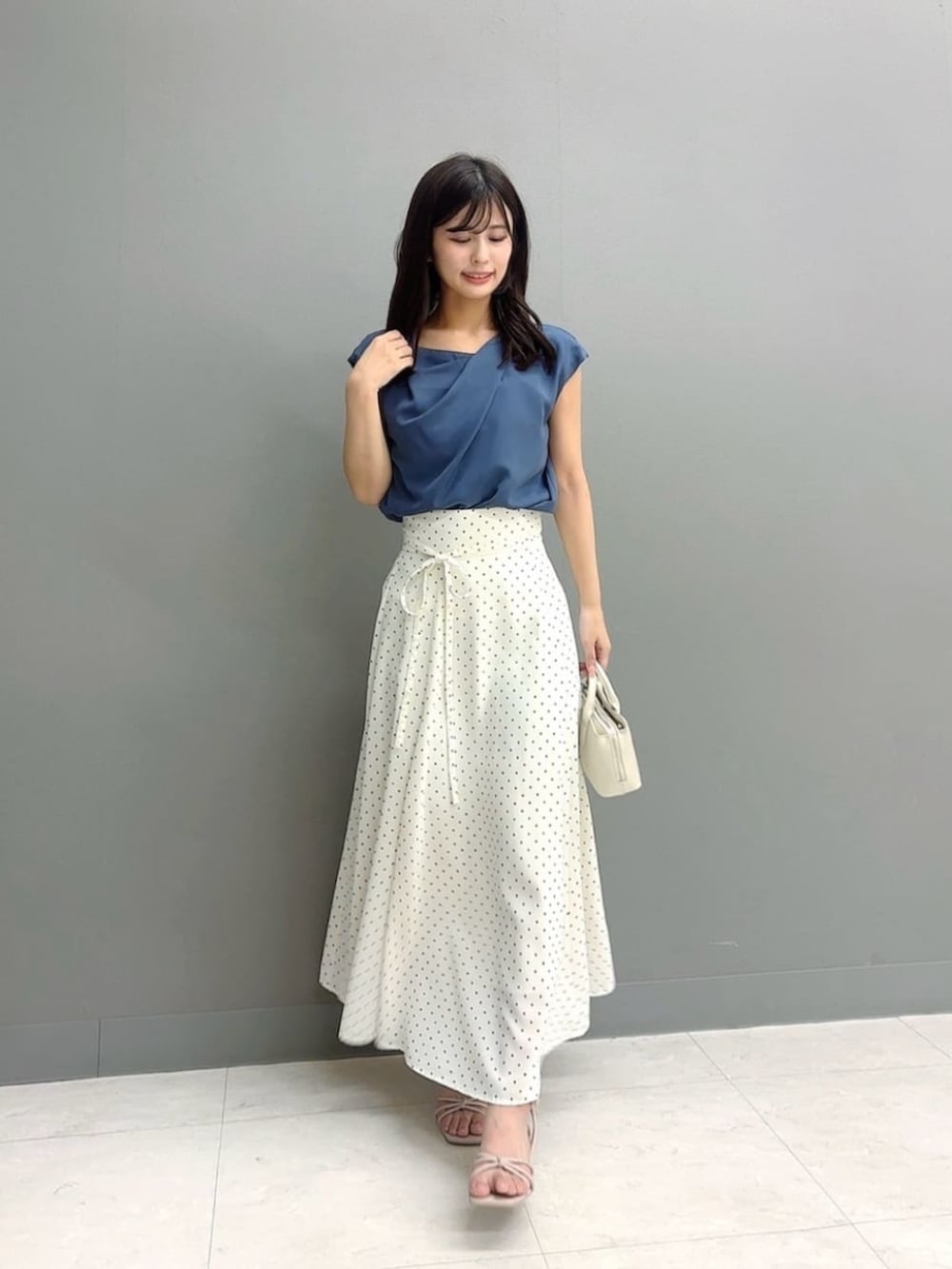 ホワイト系のトートバッグ、ブルー系のシャツ/ブラウス、ホワイト系のスカートを着用したレディースの夏コーディネートの2枚目の写真