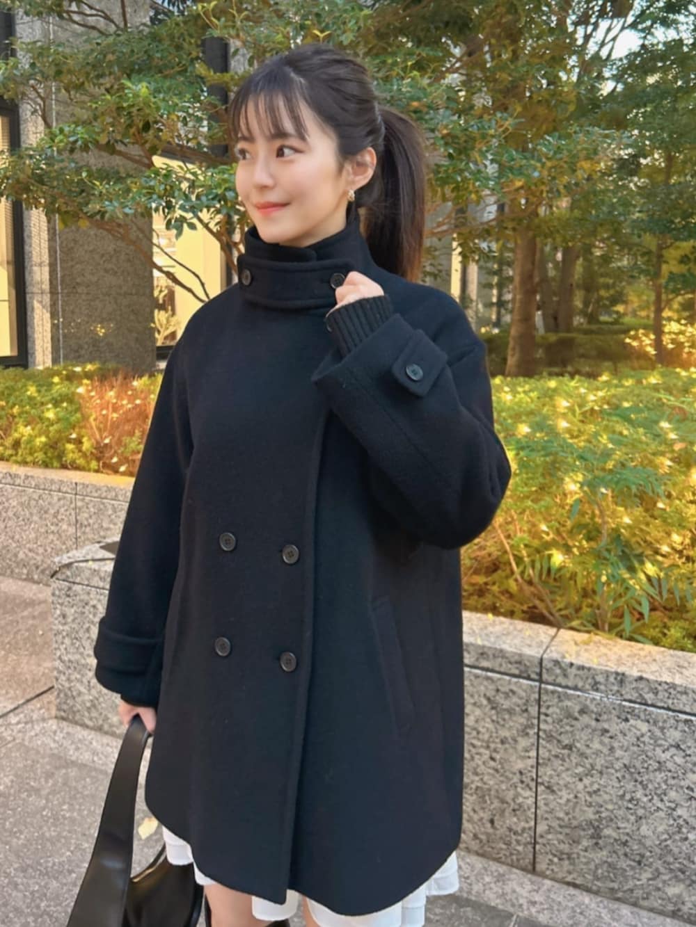 ブラック系のブーツ、ブラック系のハンドバッグ、ブラック系のピーコートを着用したレディースの冬コーディネートの3枚目の写真