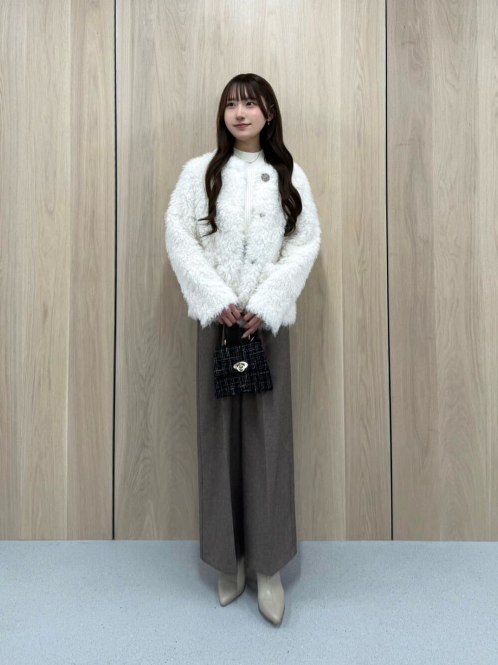 ブラック系のショルダーバッグ、ホワイト系のブルゾン、ホワイト系のニット/セーターを着用したレディースの秋コーディネートの2枚目の写真