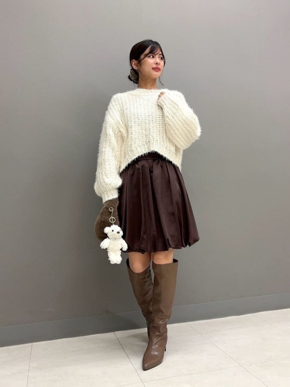 ブラウン系のブーツ、ブラウン系のハンドバッグ、ホワイト系のニット/セーターを着用したレディースの秋コーディネートの2枚目の写真