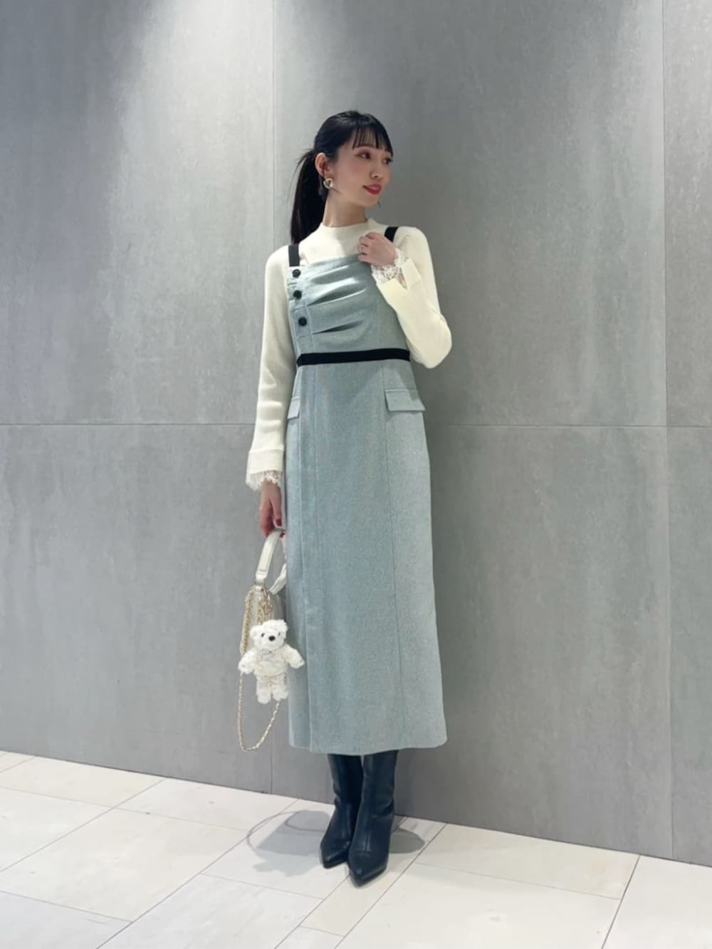 ホワイト系のショルダーバッグ、ホワイト系のニット/セーター、グレー系のワンピースを着用したレディースの冬コーディネートの2枚目の写真