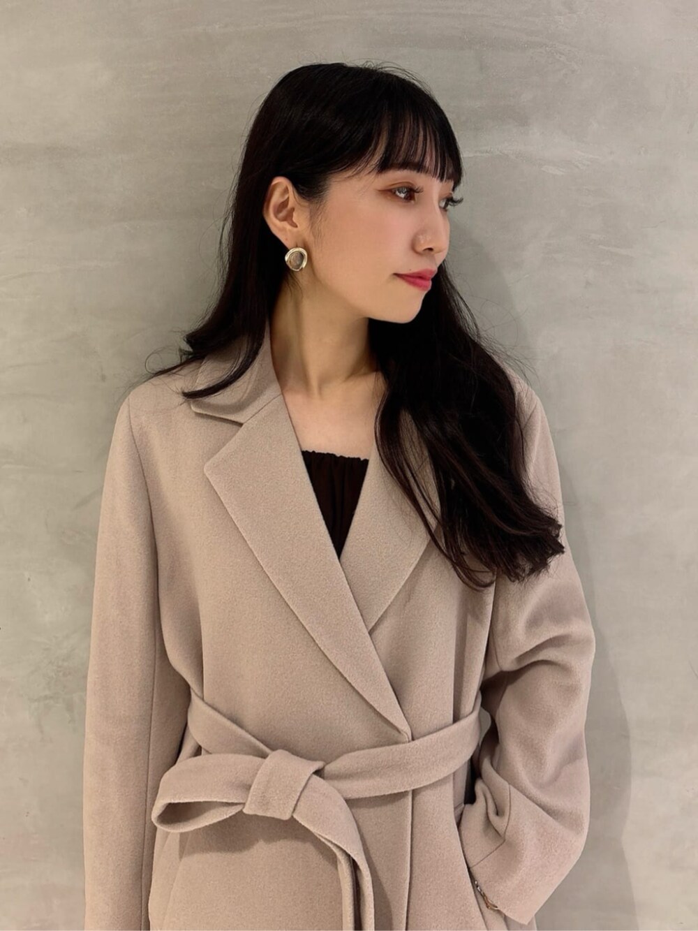 ブラック系のパンプス、ベージュ系のステンカラーコート、ブルー系のその他パンツを着用したレディースの秋コーディネートの3枚目の写真