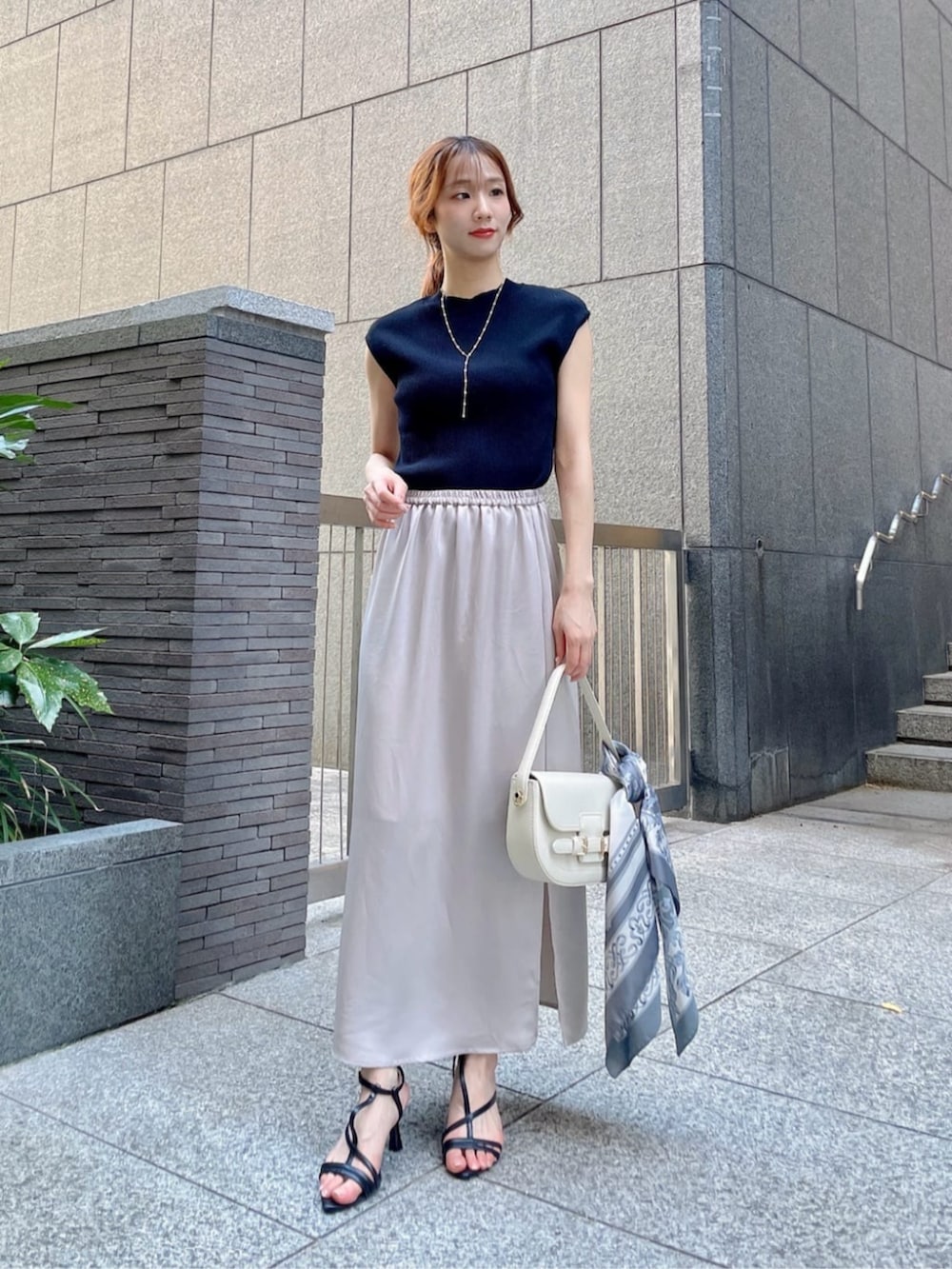 ブラック系のパンプス、ブラック系のニット/セーター、ベージュ系のスカートを着用したレディースの夏コーディネートの2枚目の写真