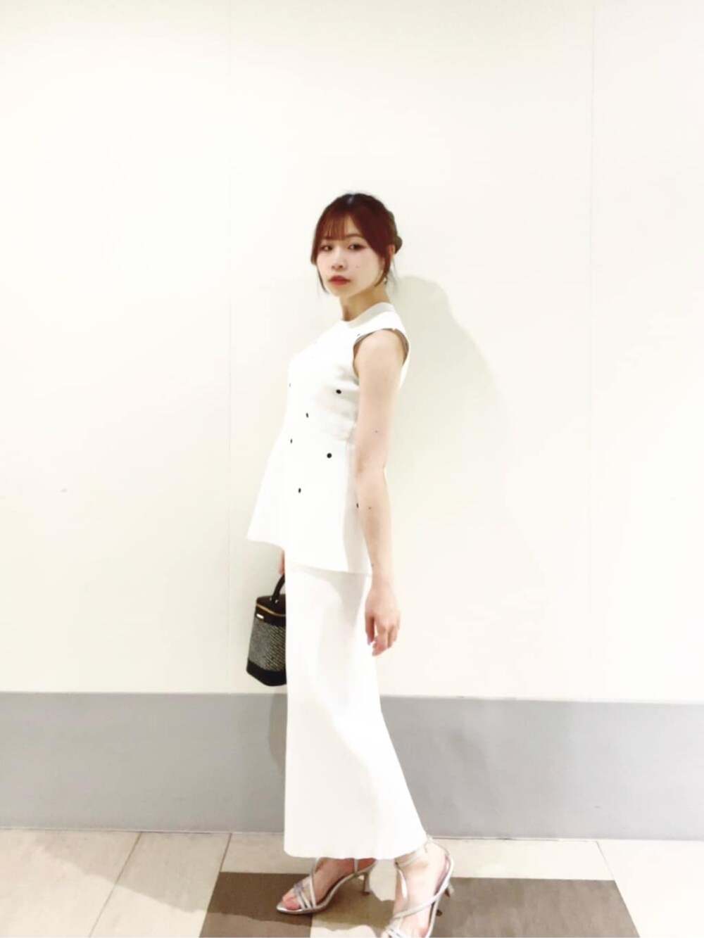 ブラック系のショルダーバッグ、ホワイト系のワンピース、シルバー系のパンプスを着用したレディースの夏コーディネートの2枚目の写真