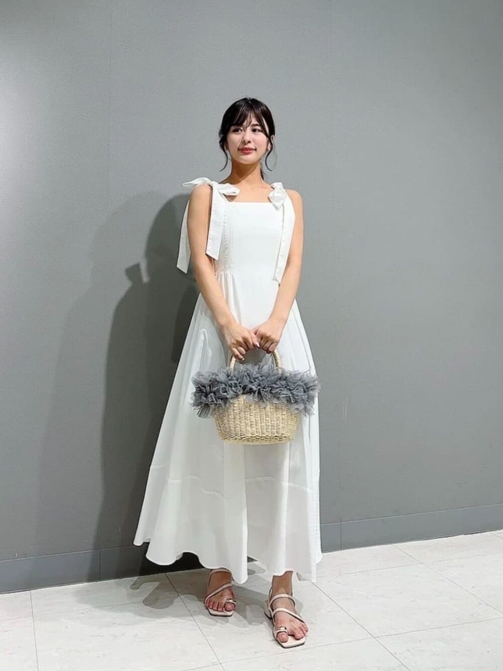 ホワイト系のパンプス、グレー系のかごバッグ、ベージュ系のカーディガン/ボレロを着用したレディースの春コーディネートの2枚目の写真