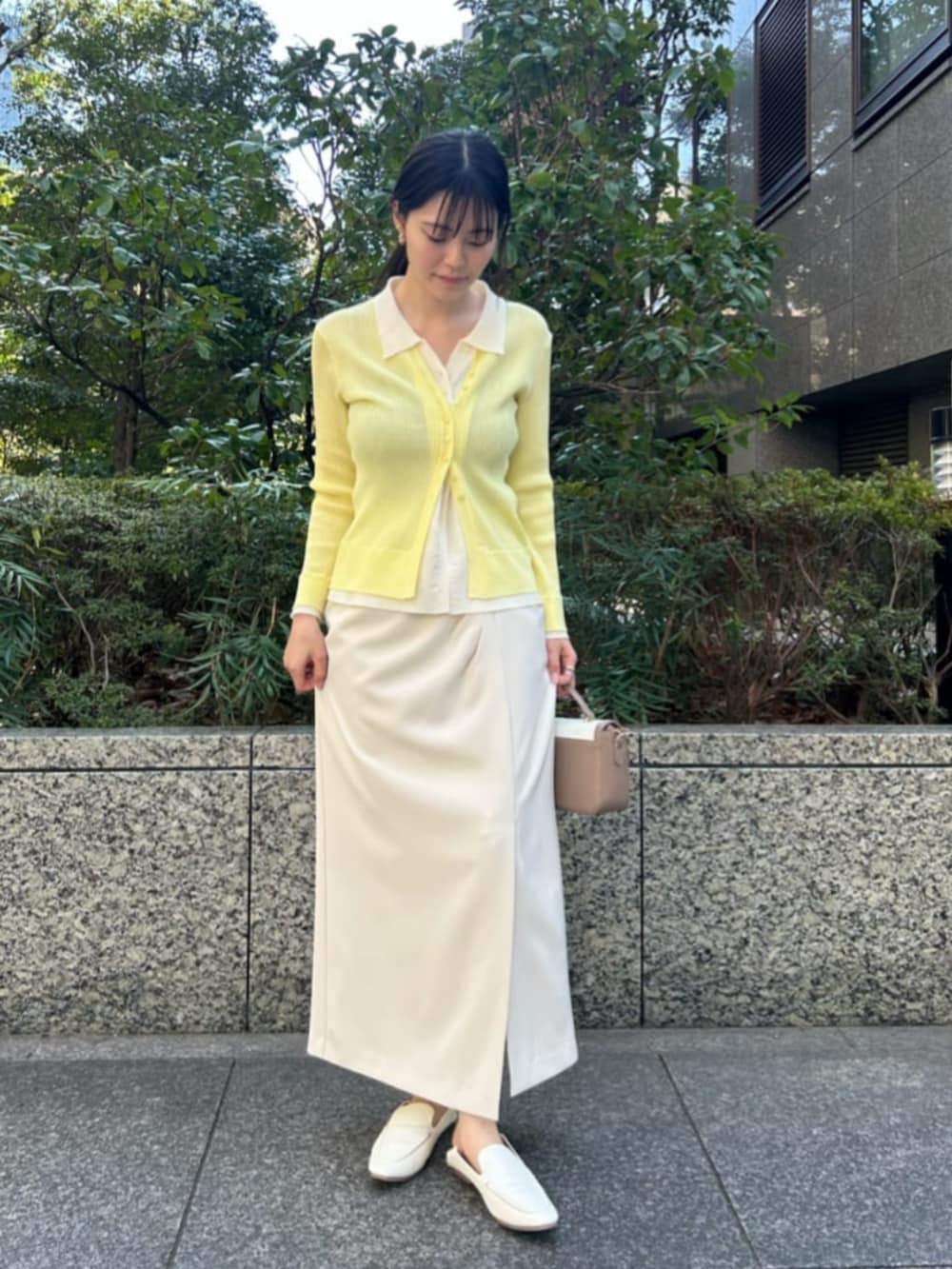 イエロー系のニット/セーター、ホワイト系のスカートを着用したレディースの春コーディネートの3枚目の写真