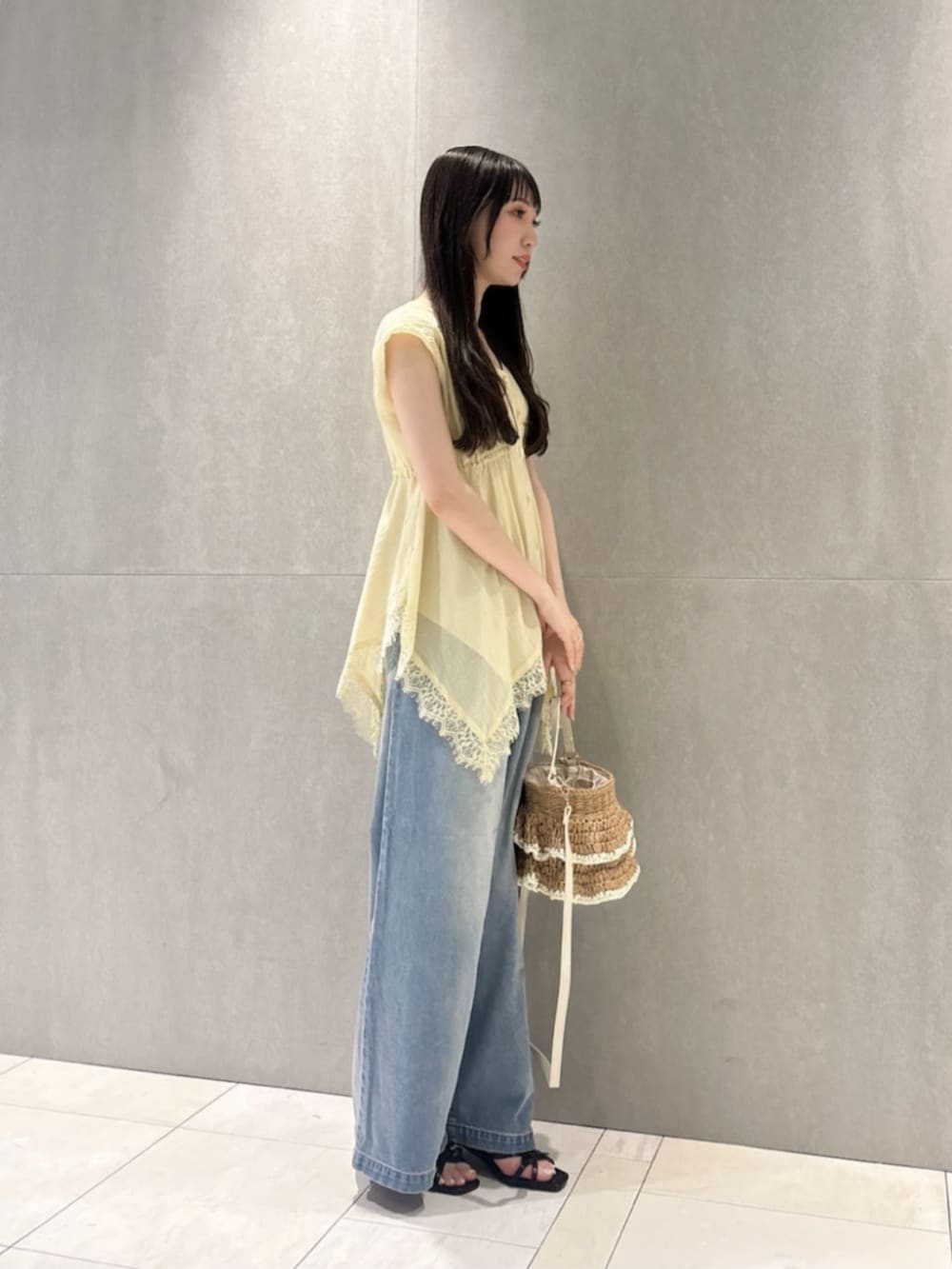 イエロー系のシャツ/ブラウス、ブルー系のその他パンツ、ベージュ系のショルダーバッグを着用したレディースの春コーディネートの2枚目の写真