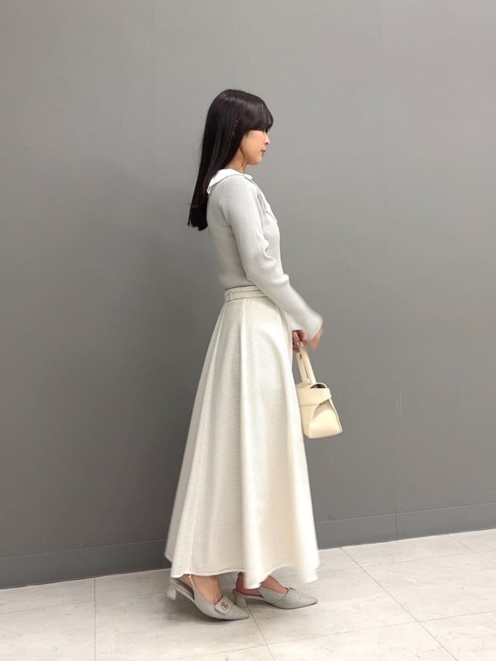 ホワイト系のトートバッグ、グレー系のニット/セーター、ホワイト系のスカートを着用したレディースの冬コーディネートの2枚目の写真