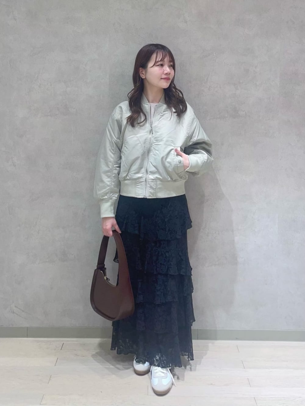 ブラック系のスカート、ブラウン系のハンドバッグ、グリーン系のブルゾンを着用したレディースの冬コーディネートの2枚目の写真