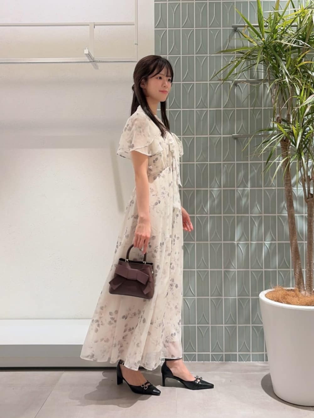 ブラック系のパンプス、ベージュ系のワンピース、ブラウン系のショルダーバッグを着用したレディースの夏コーディネートの2枚目の写真