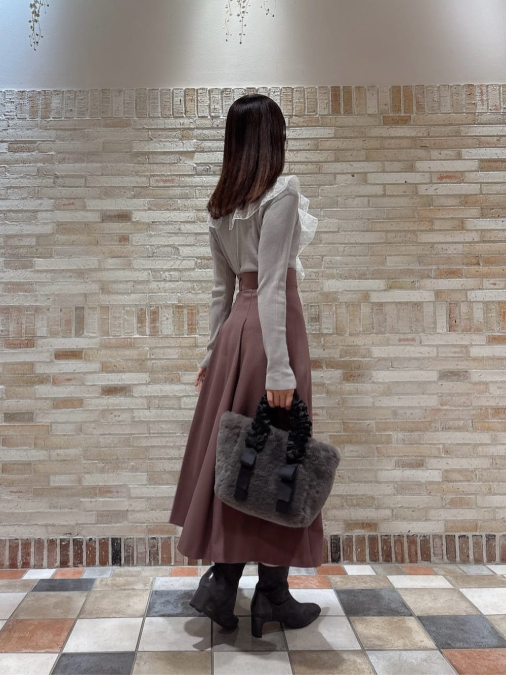グレー系のトートバッグ、グレー系のニット/セーター、ピンク系のスカートを着用したレディースの秋コーディネートの3枚目の写真
