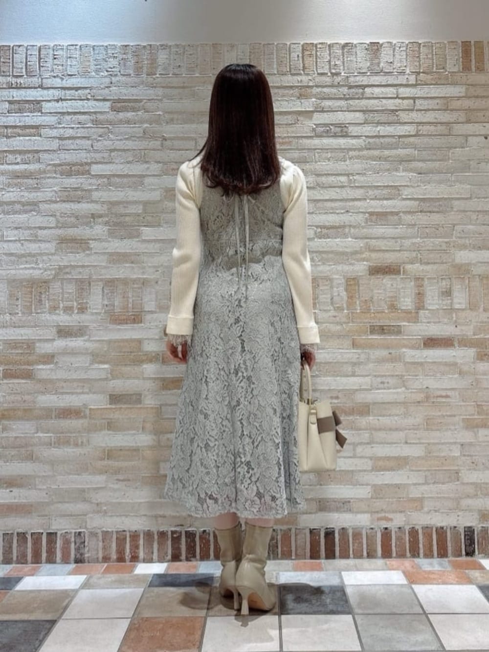 ホワイト系のニット/セーター、ベージュ系のショルダーバッグ、グリーン系のワンピースを着用したレディースの冬コーディネートの3枚目の写真