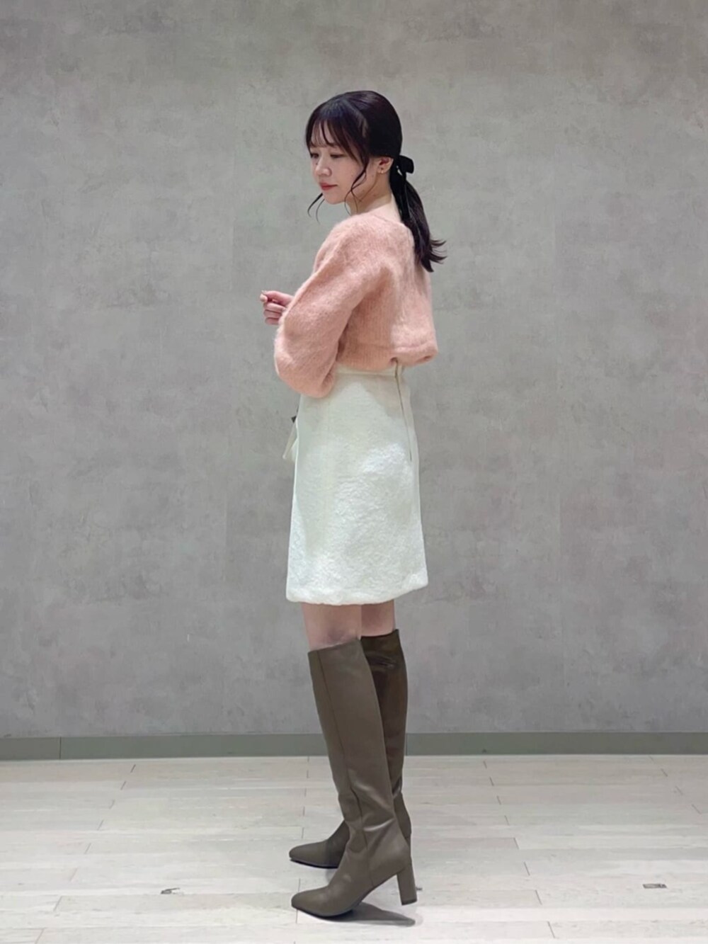 ベージュ系のショルダーバッグ、ピンク系のニット/セーター、ホワイト系のスカートを着用したレディースの冬コーディネートの3枚目の写真