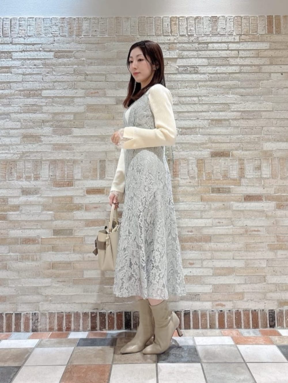 ホワイト系のニット/セーター、ベージュ系のショルダーバッグ、グリーン系のワンピースを着用したレディースの冬コーディネートの2枚目の写真