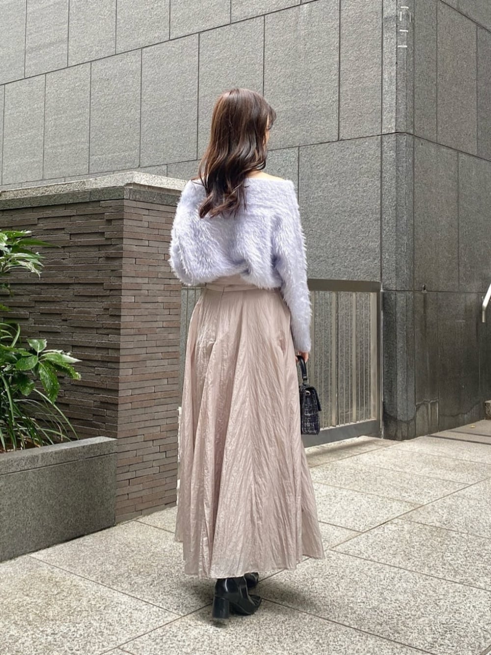 ブラック系のショルダーバッグ、ブルー系のニット/セーター、グレー系のスカートを着用したレディースの秋コーディネートの2枚目の写真