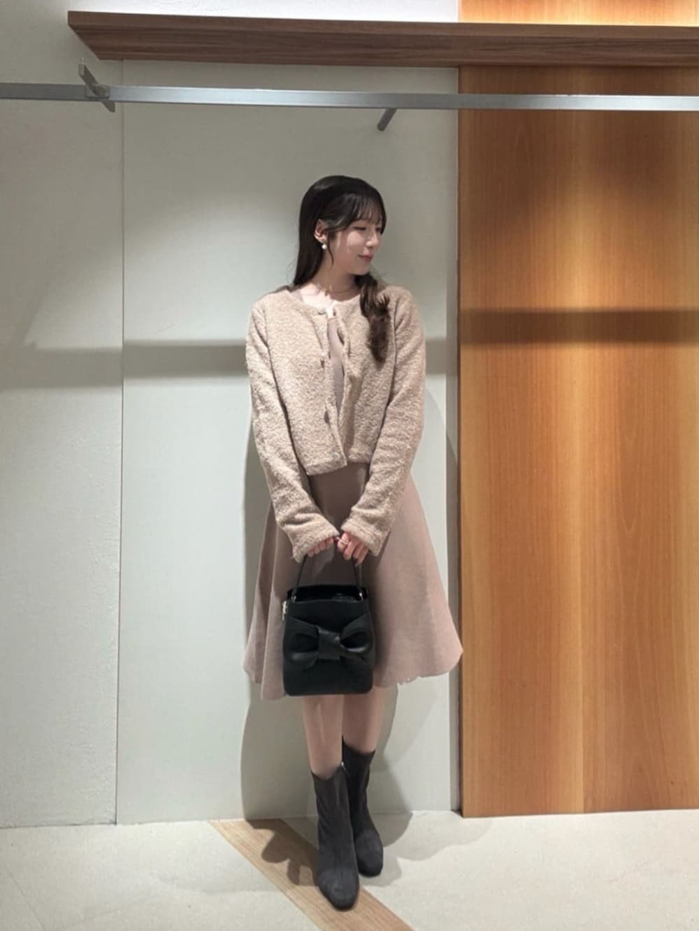 ベージュ系のニット/セーター、ベージュ系のワンピース、ブラック系のショルダーバッグを着用したレディースの秋コーディネートの2枚目の写真