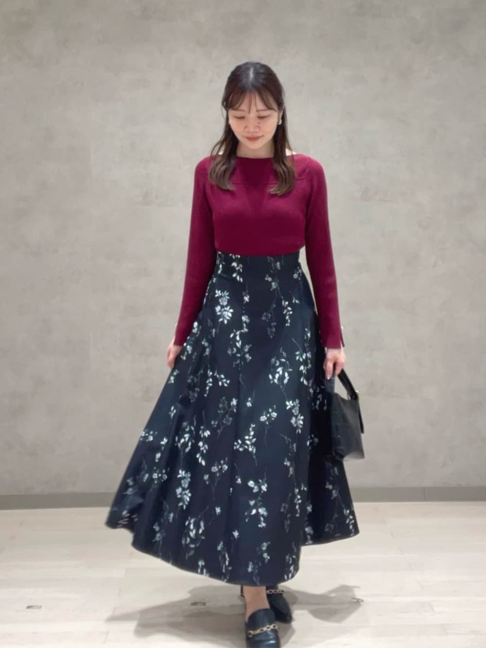 ブラック系のスカート、レッド系のニット/セーターを着用したレディースの秋コーディネートの2枚目の写真