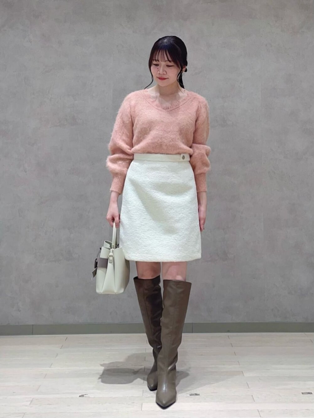 ベージュ系のショルダーバッグ、ピンク系のニット/セーター、ホワイト系のスカートを着用したレディースの冬コーディネートの2枚目の写真