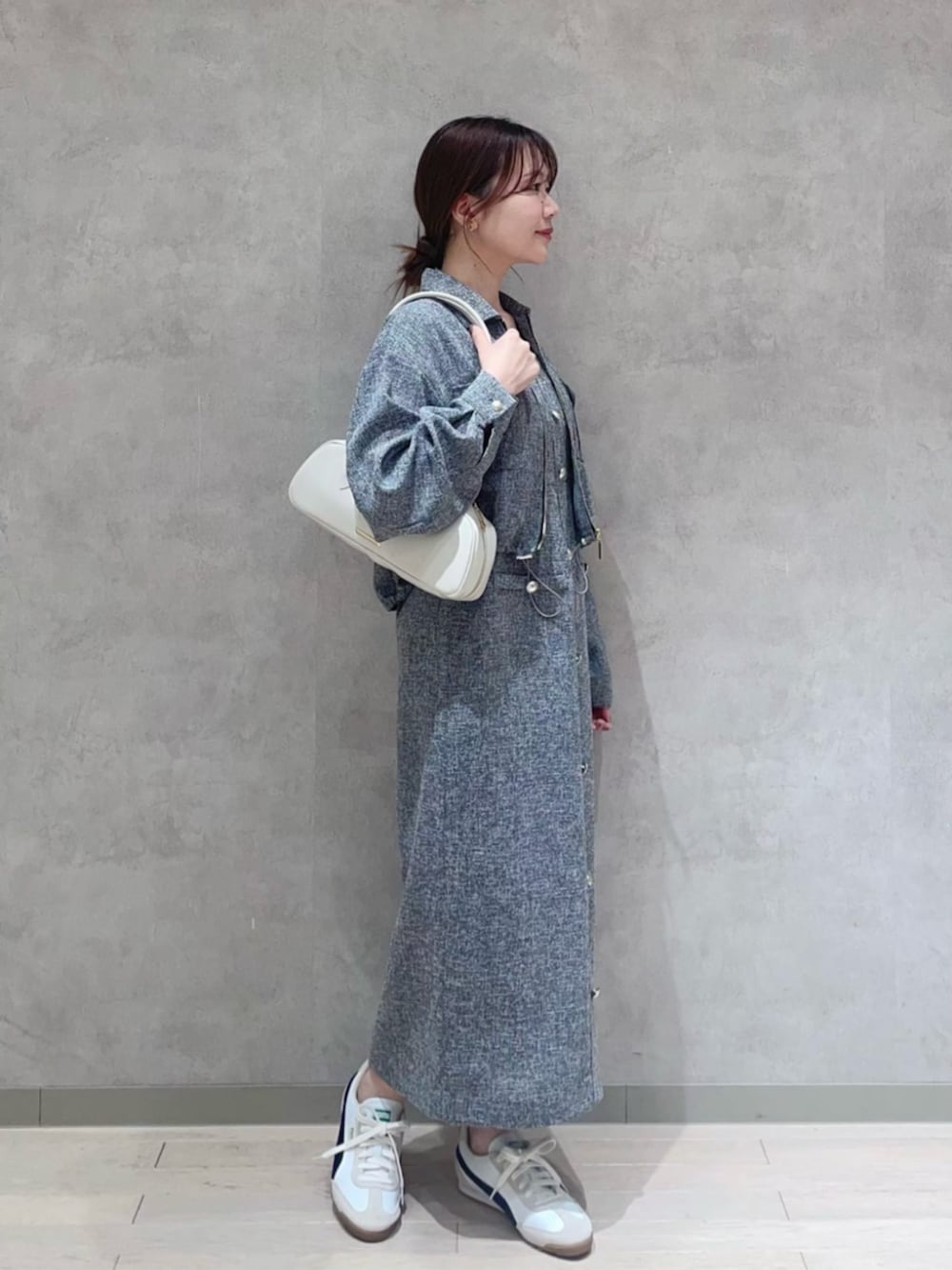 ホワイト系のショルダーバッグ、ブラック系のブルゾン、ブラック系のジャンパースカートを着用したレディースの春コーディネートの2枚目の写真