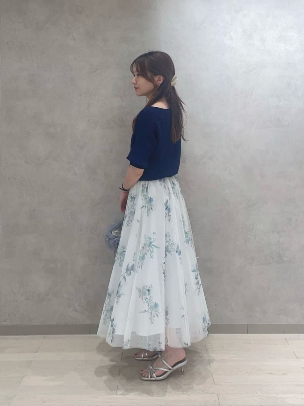 ブルー系のスカート、シルバー系のパンプス、ブルー系のニット/セーターを着用したレディースの春コーディネートの2枚目の写真