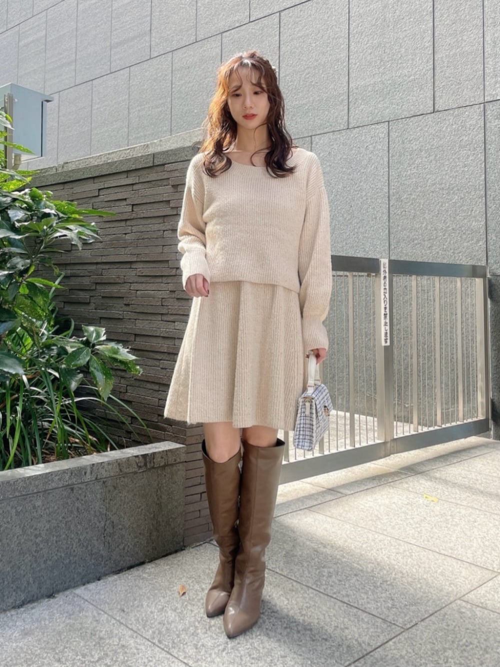 ホワイト系のショルダーバッグ、ブラウン系のブーツ、ベージュ系のワンピースを着用したレディースの冬コーディネートの3枚目の写真