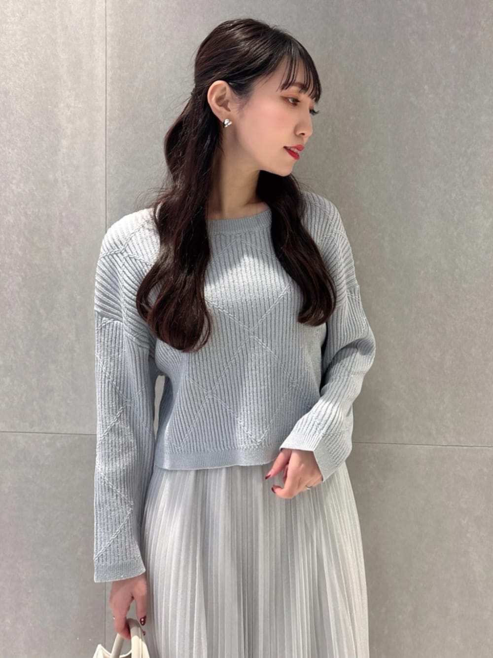 ホワイト系のショルダーバッグ、ブルー系のニット/セーター、グレー系のスカートを着用したレディースの春コーディネートの3枚目の写真