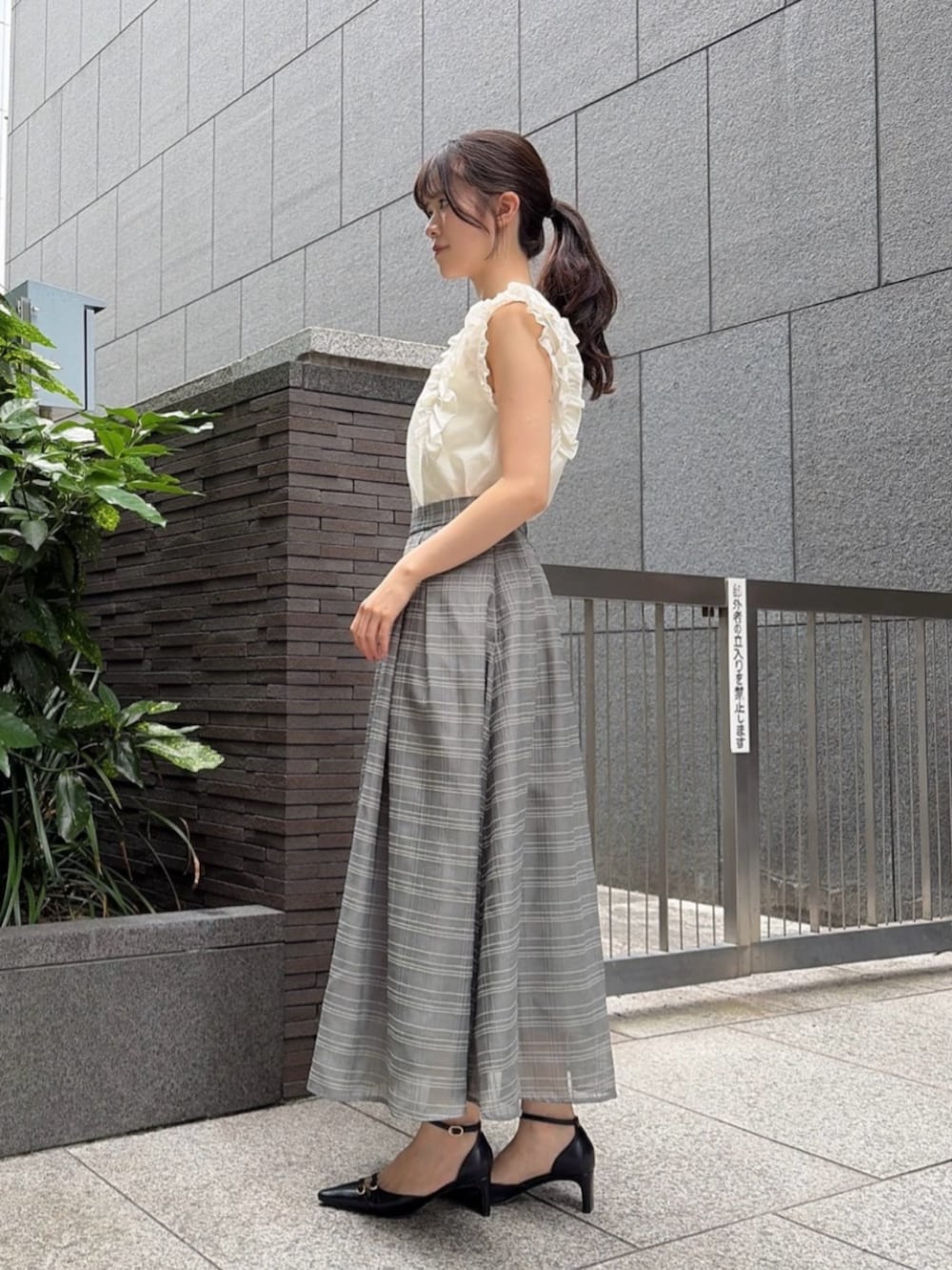 ブラック系のパンプス、ホワイト系のショルダーバッグ、ホワイト系のシャツ/ブラウスを着用したレディースの夏コーディネートの2枚目の写真