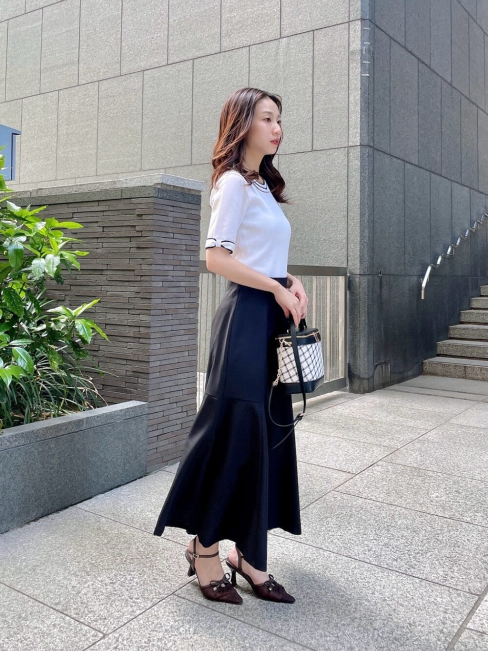 ホワイト系のニット/セーター、ブラック系のスカートを着用したレディースの春コーディネートの2枚目の写真