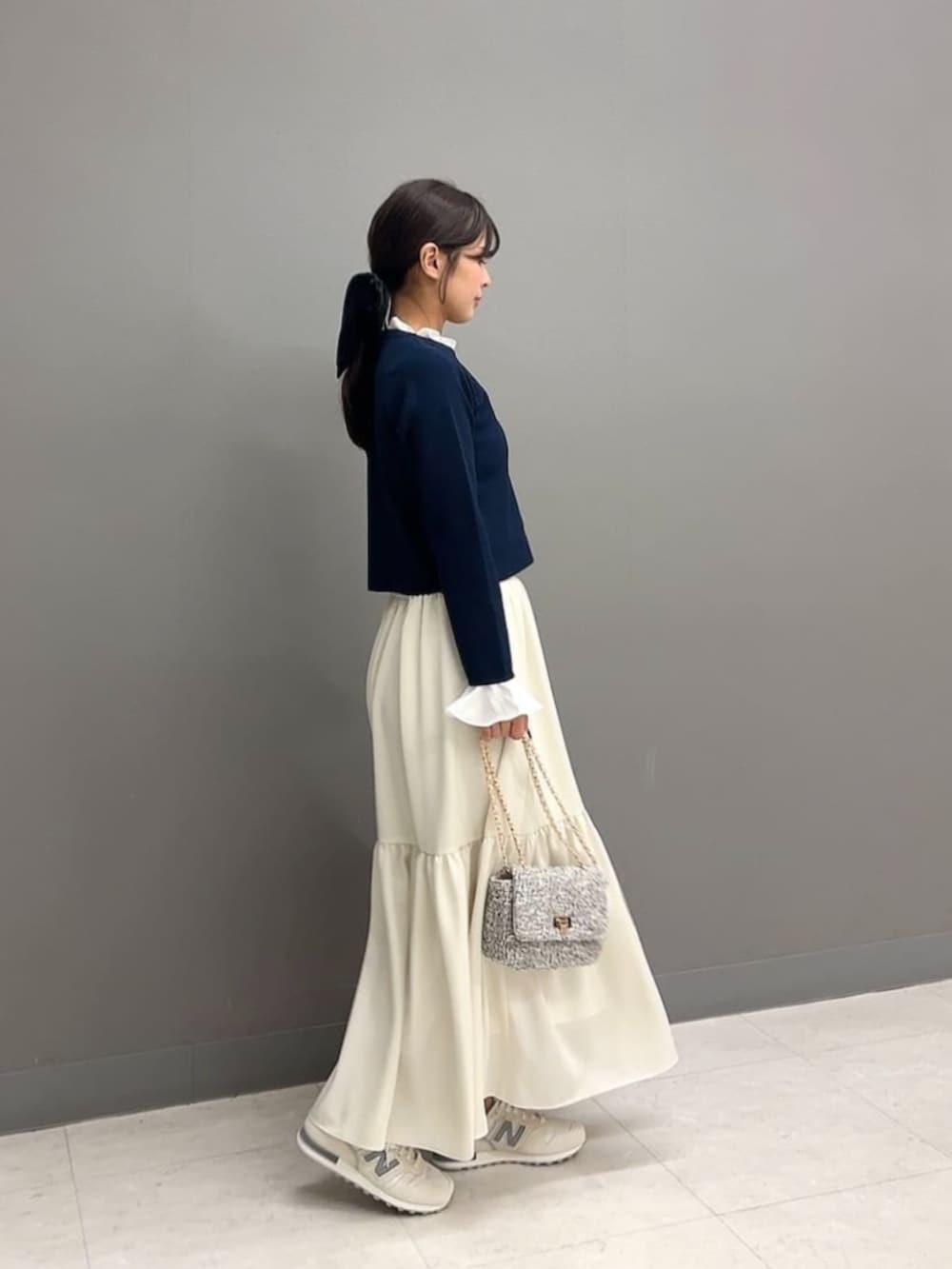 ブルー系のカーディガン/ボレロ、ホワイト系のスカート、ブラック系のショルダーバッグを着用したレディースの春コーディネートの2枚目の写真