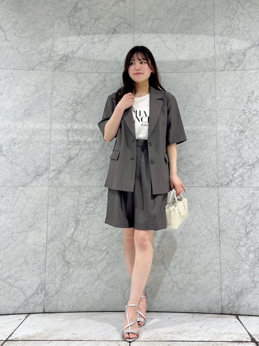ホワイト系のTシャツ/カットソー、シルバー系のパンプス、グレー系のテーラードジャケットを着用したレディースの春コーディネートの3枚目の写真