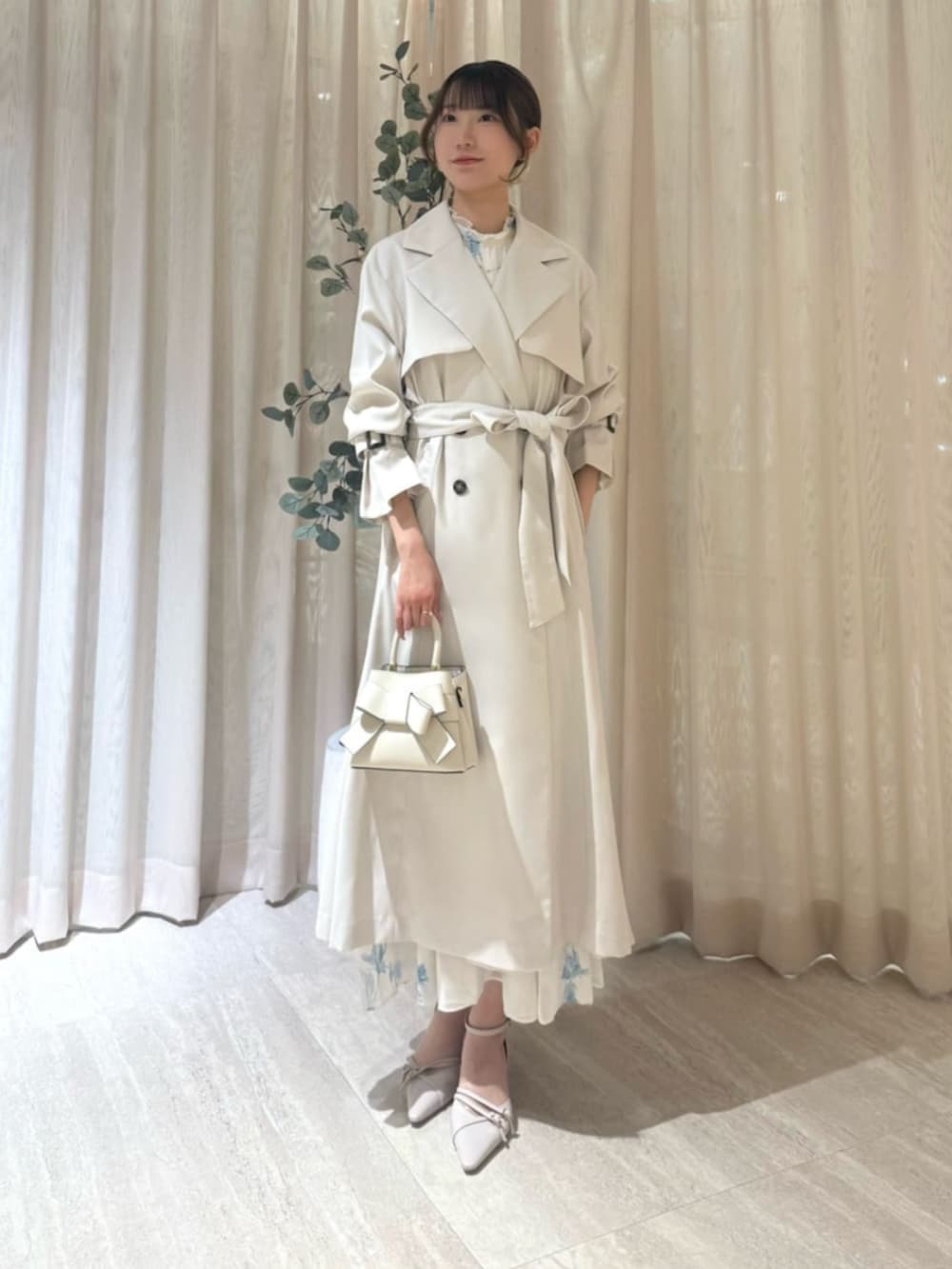 ホワイト系のパンプス、ホワイト系のトレンチコート、ブルー系のワンピースを着用したレディースの春コーディネートの2枚目の写真