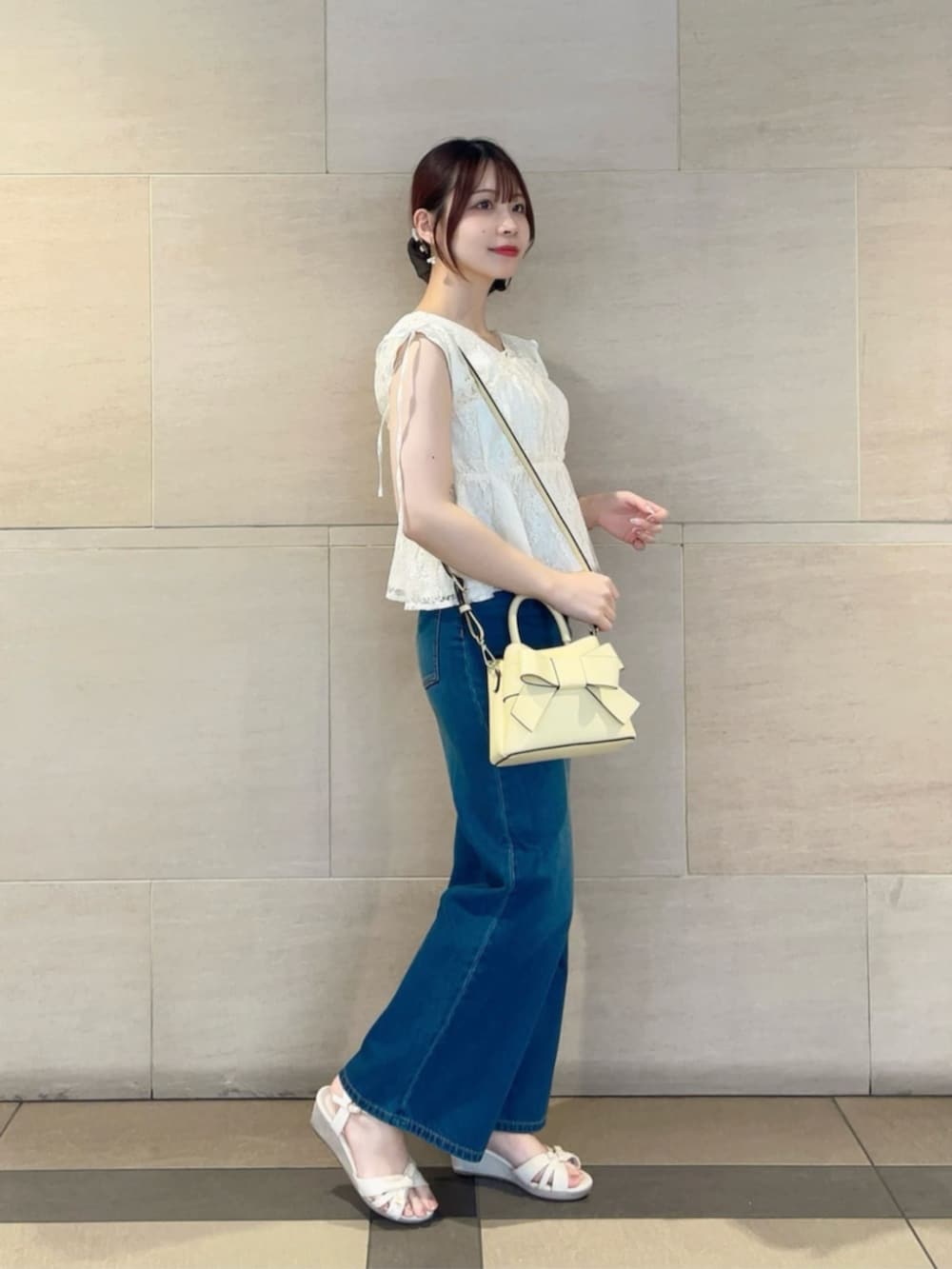 イエロー系のショルダーバッグ、ホワイト系のシャツ/ブラウス、ブルー系のデニムパンツを着用したレディースの夏コーディネートの2枚目の写真