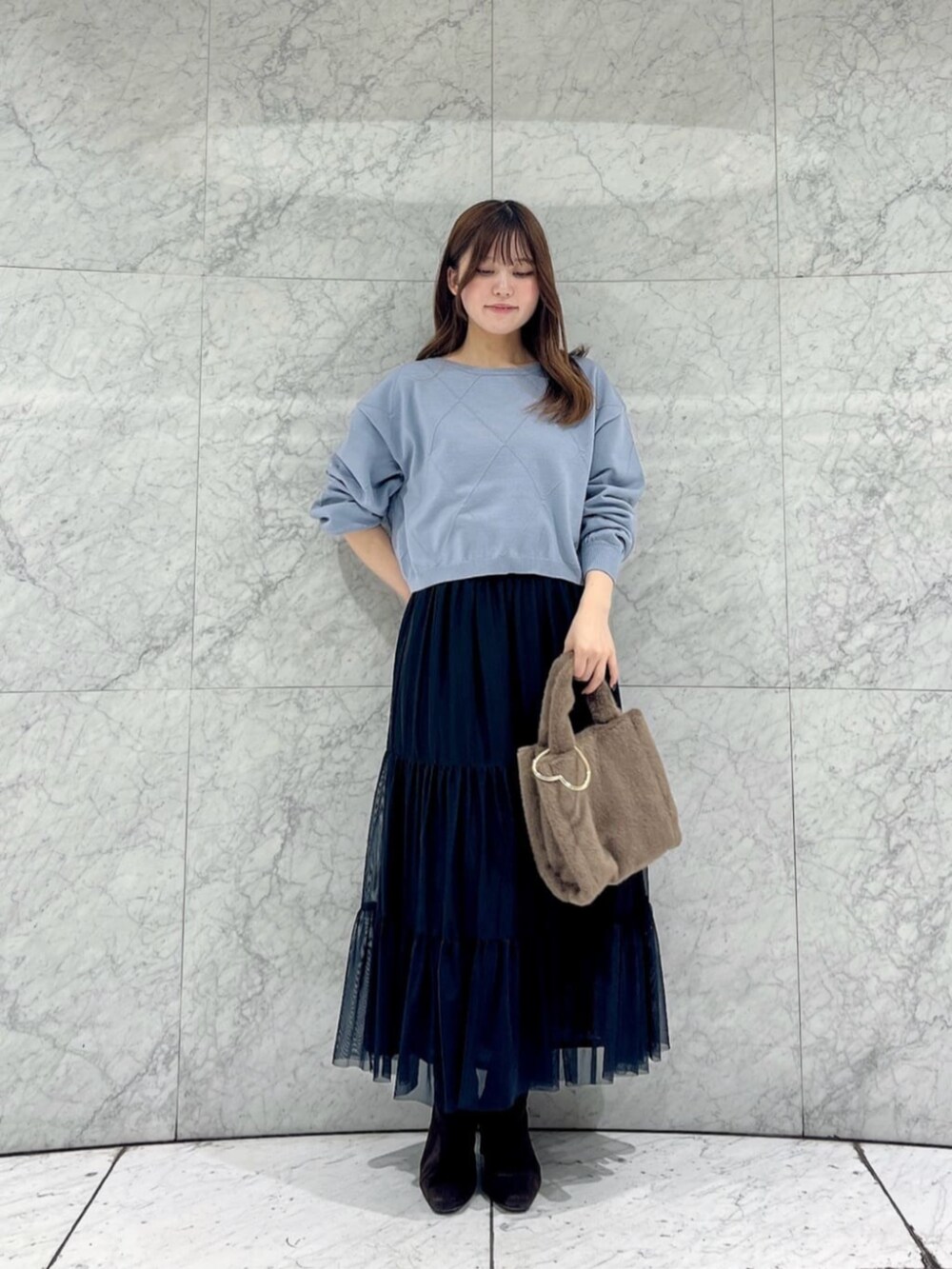 ブルー系のニット/セーター、ブラック系のスカート、ブラウン系のトートバッグを着用したレディースの秋コーディネートの3枚目の写真