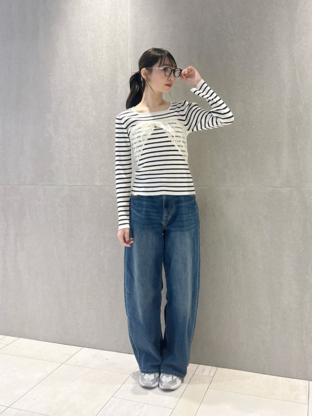 ブルー系のデニムパンツ、ホワイト系のショルダーバッグ、ホワイト系のニット/セーターを着用したレディースの春コーディネートの2枚目の写真