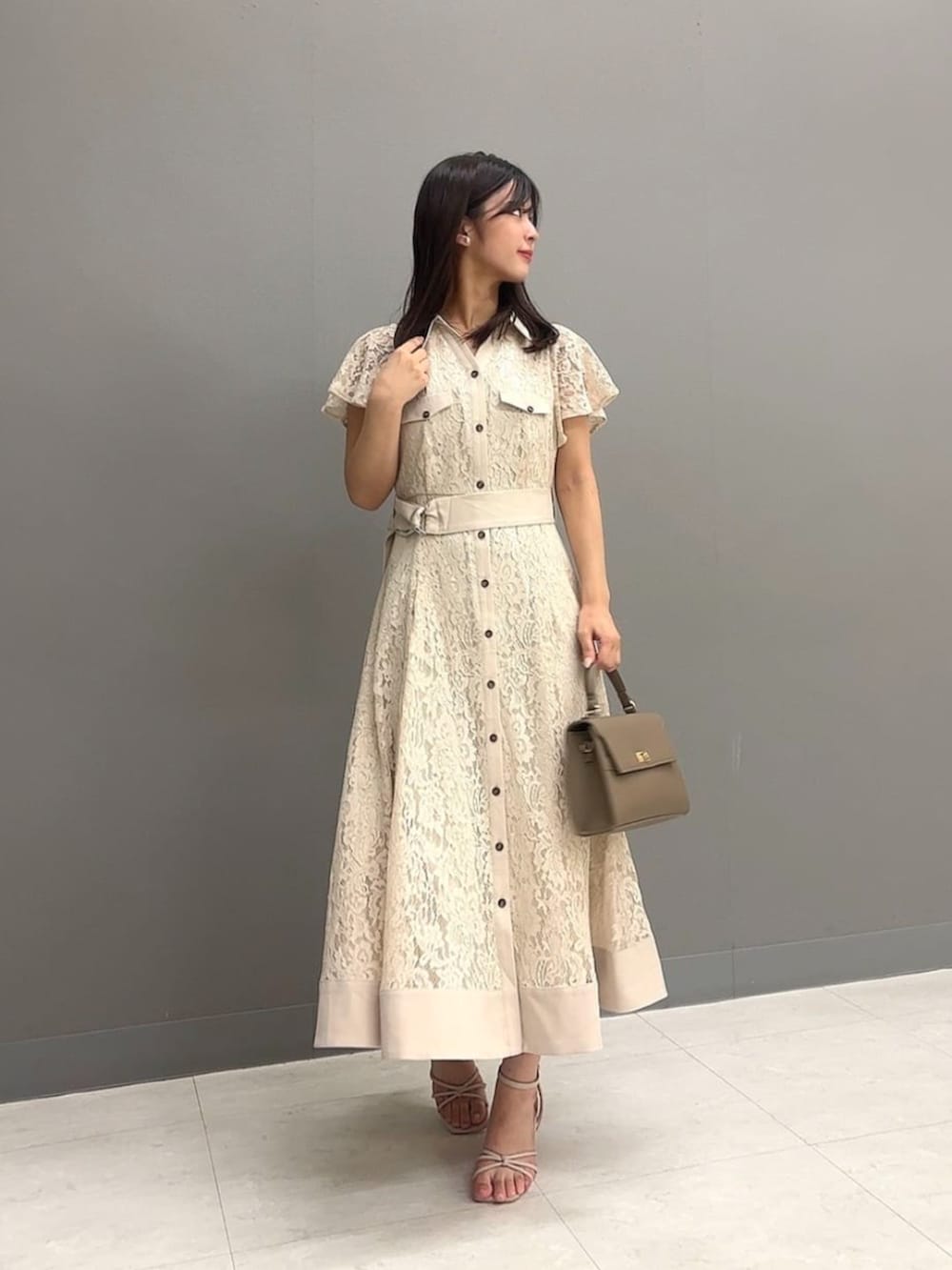 ブラウン系のショルダーバッグ、ベージュ系のワンピースを着用したレディースの夏コーディネートの2枚目の写真