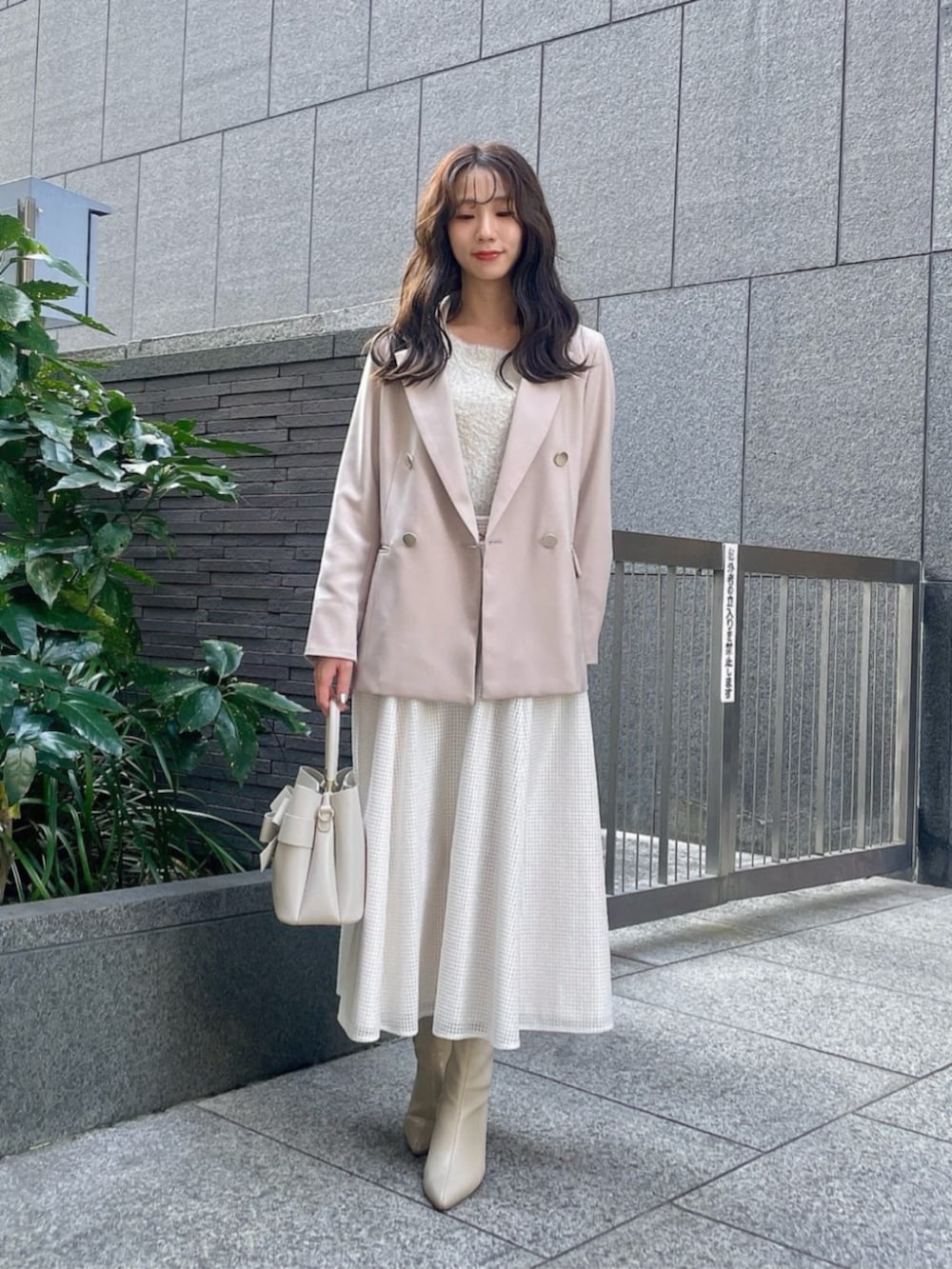 ホワイト系のスカート、ベージュ系のテーラードジャケット、ベージュ系のニット/セーターを着用したレディースの冬コーディネートの2枚目の写真