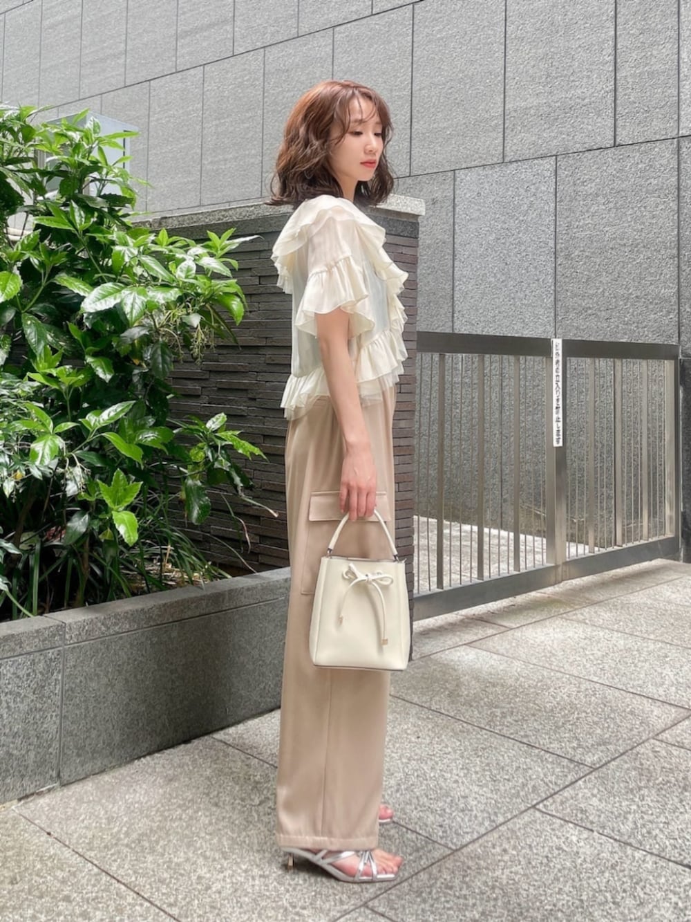 ホワイト系のショルダーバッグ、シルバー系のパンプス、ホワイト系のシャツ/ブラウスを着用したレディースの春コーディネートの2枚目の写真
