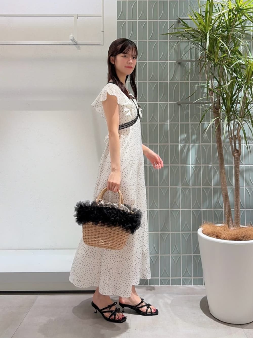 ブラック系のパンプス、ブラック系のショルダーバッグ、ホワイト系のワンピースを着用したレディースの夏コーディネートの2枚目の写真