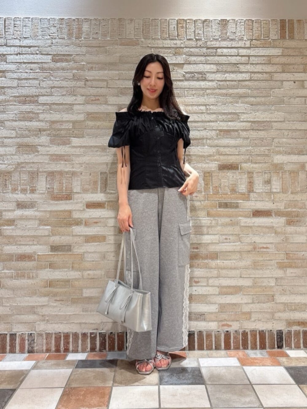 シルバー系のパンプス、シルバー系のショルダーバッグ、ブラック系のシャツ/ブラウスを着用したレディースの夏コーディネートの2枚目の写真