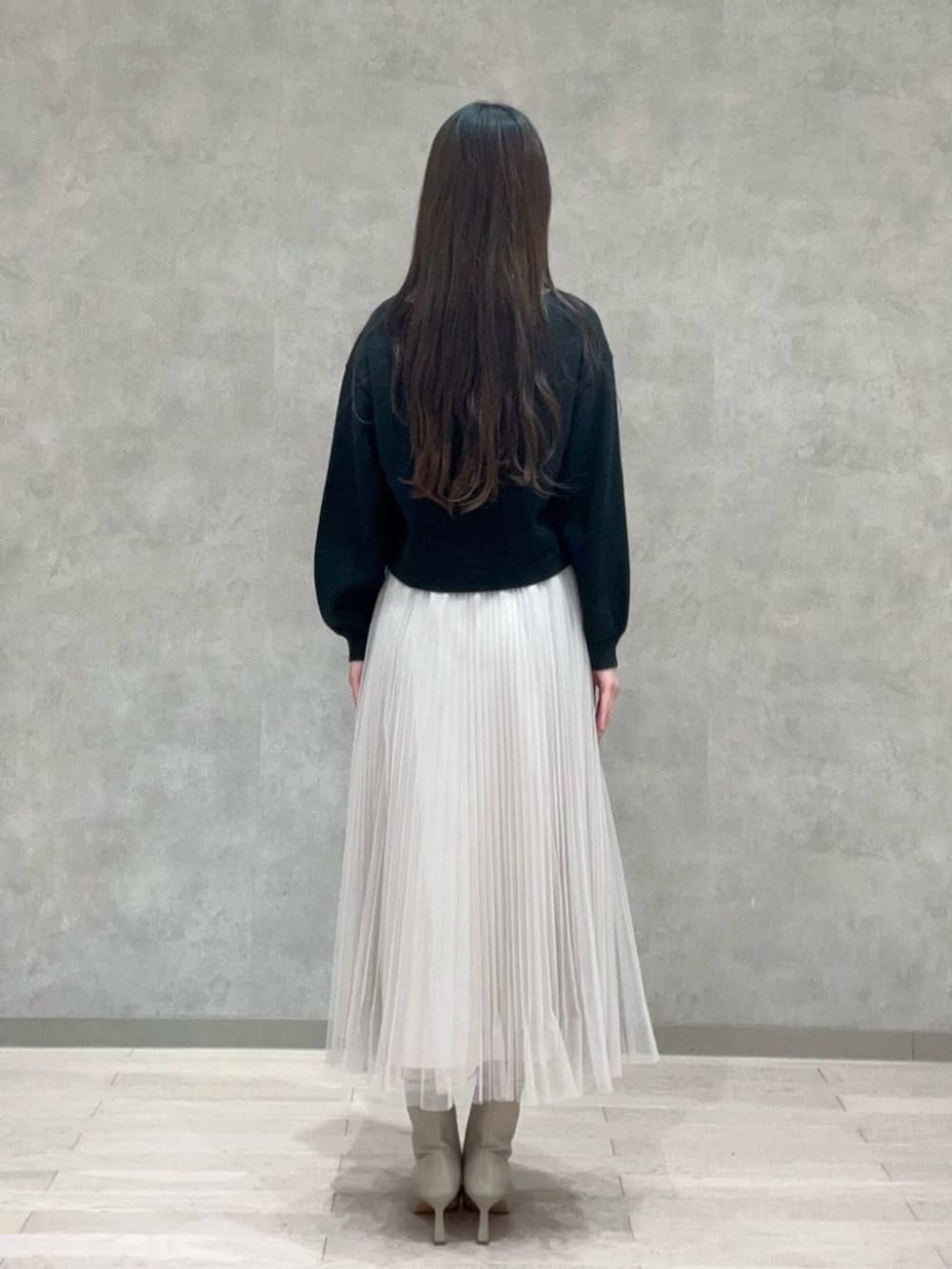 グレー系のトートバッグ、ブラック系のニット/セーター、ホワイト系のスカートを着用したレディースの冬コーディネートの3枚目の写真