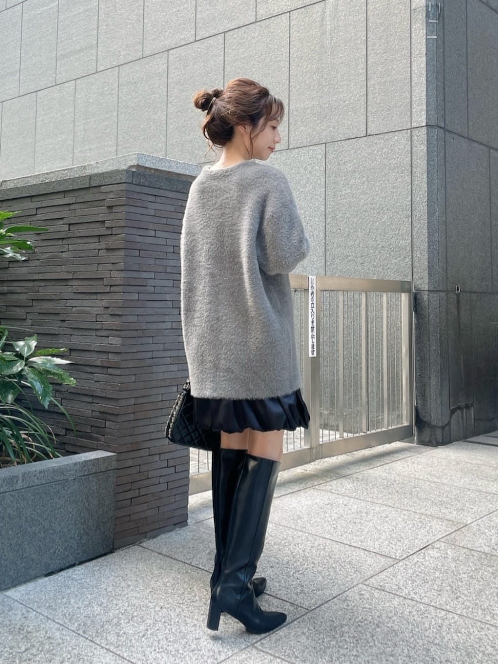 グレー系のテーラードジャケット、ブラック系のスカート、ブラック系のブーツを着用したレディースの秋コーディネートの2枚目の写真
