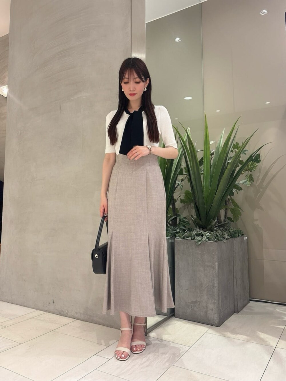 ブラック系のショルダーバッグ、ブラウン系のスカート、ホワイト系のニット/セーターを着用したレディースの夏コーディネートの3枚目の写真