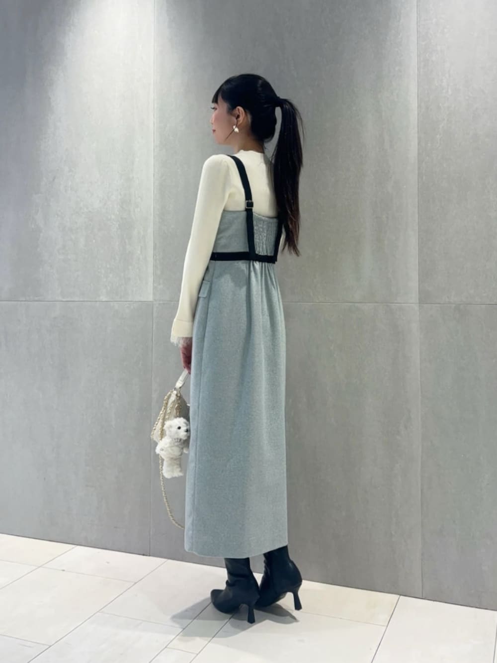 ホワイト系のショルダーバッグ、ホワイト系のニット/セーター、グレー系のワンピースを着用したレディースの冬コーディネートの3枚目の写真
