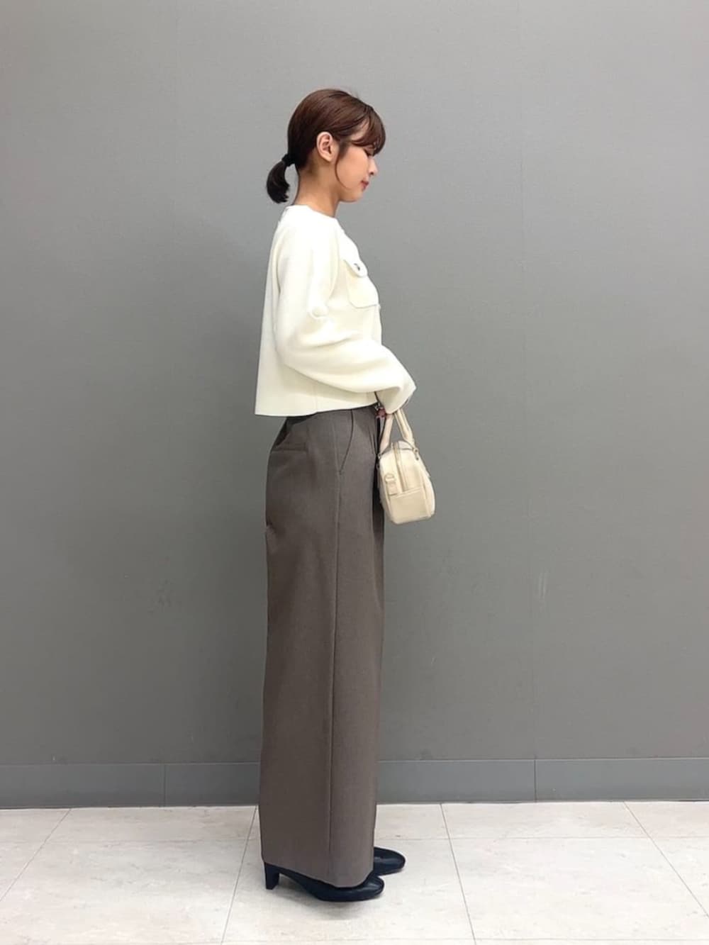 ホワイト系のボストンバッグ、ホワイト系のカーディガン/ボレロ、ブラウン系のその他パンツを着用したレディースの秋コーディネートの3枚目の写真