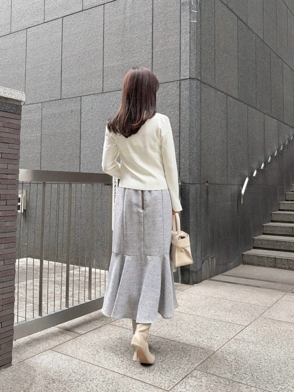 ホワイト系のトートバッグ、ホワイト系のニット/セーター、ブラック系のスカートを着用したレディースの冬コーディネートの3枚目の写真